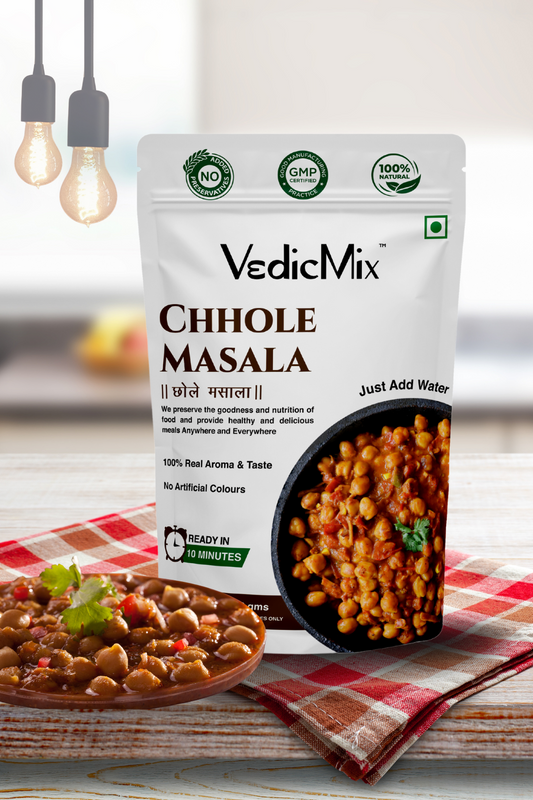 Packaging of VedicMix Chhole Masala with an image of prepared chickpeas dish in the background, placed on a checkered tablecloth.
